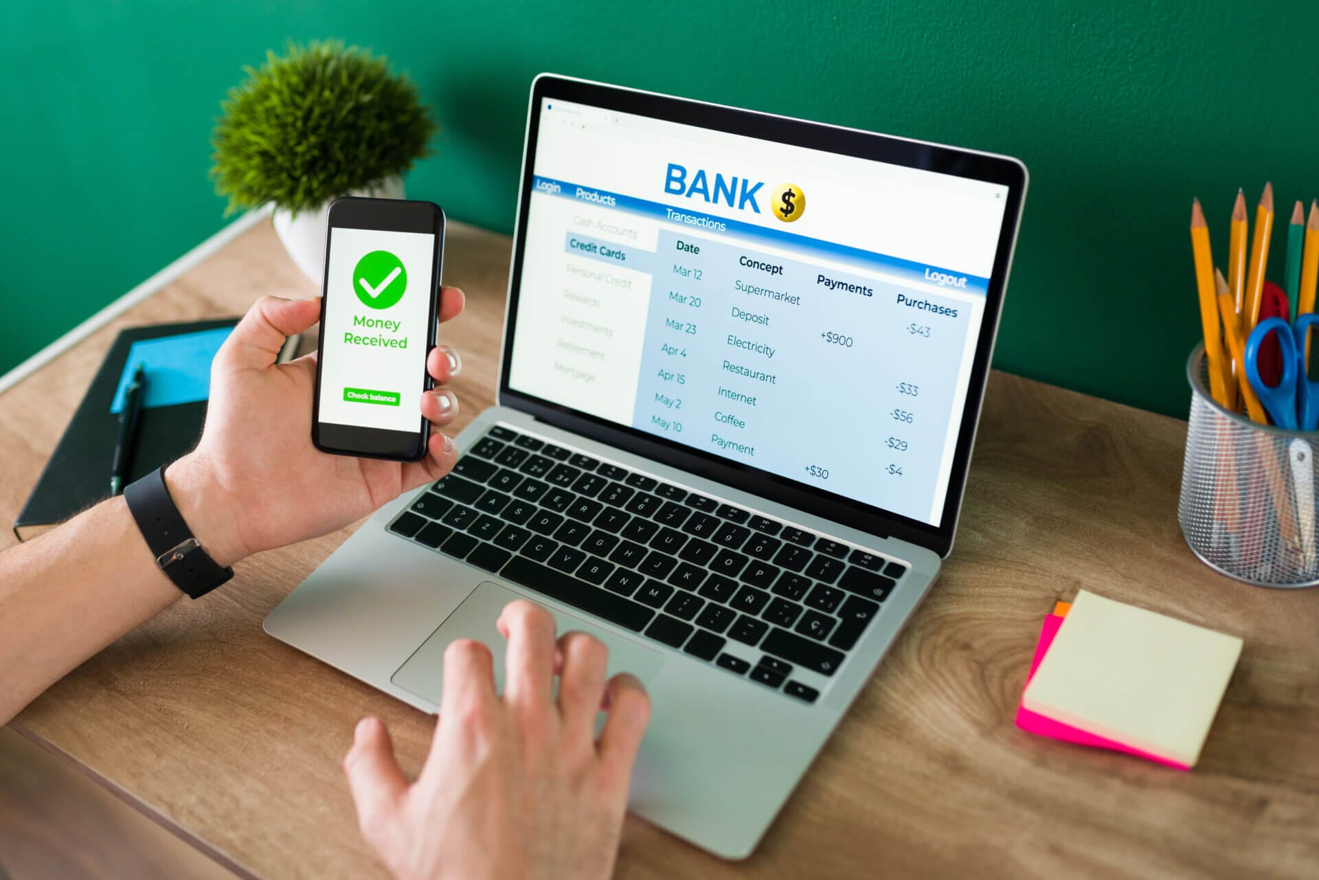 Person doing an online bank transaction Wire transfer. Young man using his smartphone and laptop to do a banking transaction and some payments